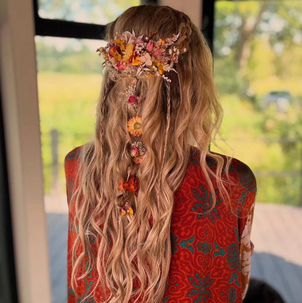 Long blonde waves with a colourful dried-flower crown and trailing floral braid.