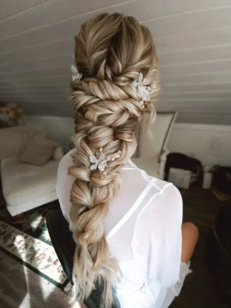 Extra-long blonde bridal braid with large sculpted sections and delicate pearl accents.
