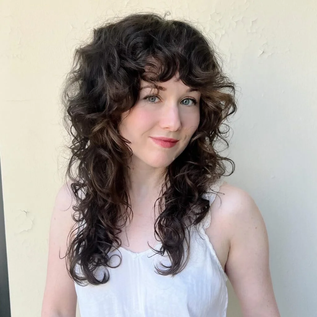 Medium curly shag haircut with soft wispy bangs