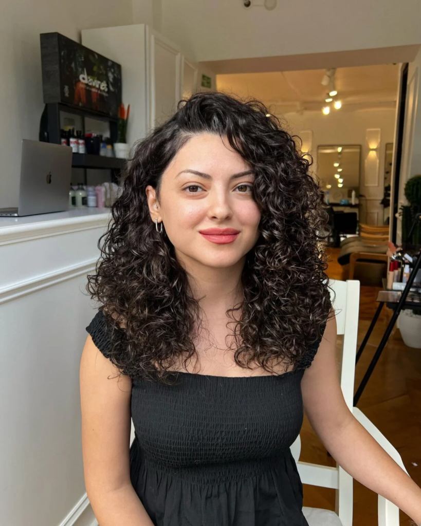 Shoulder-length side-parted curly hairstyle for round faces