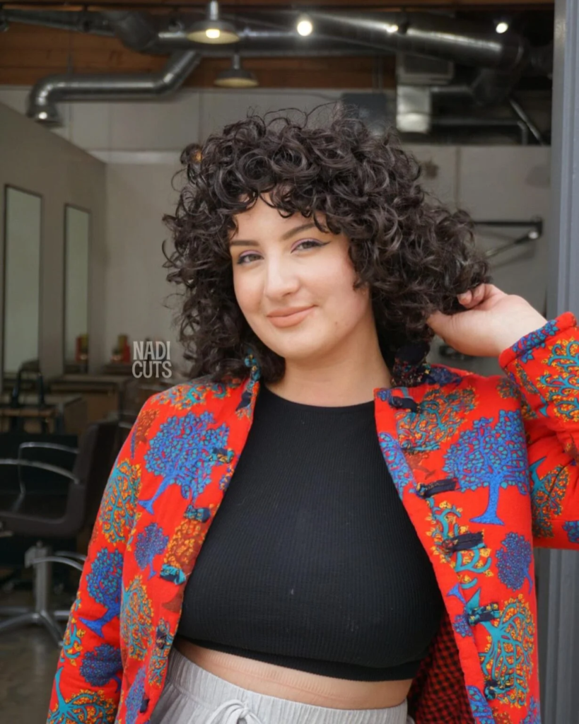 Short curly bob with full bangs for round faces