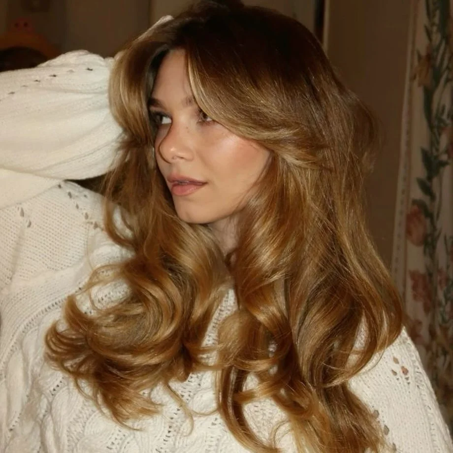 Long layered blowout with curtain bangs and voluminous golden brown curls