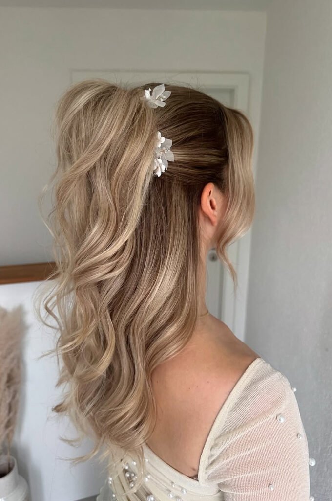 High blonde half-up ponytail with white floral hair pins and loose waves