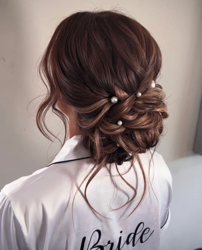 Romantic low messy bun wedding hairstyle with soft twists and loose strands, viewed from behind.