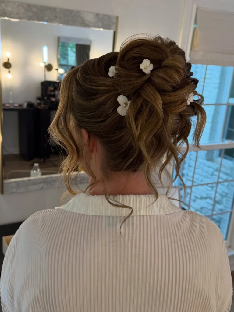 Flower-studded high messy bun with large loops and loose curled tendrils