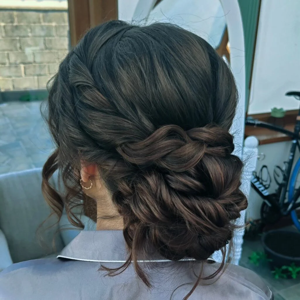 Brunette twisted low bun with rope-like sections and loose face-framing tendrils