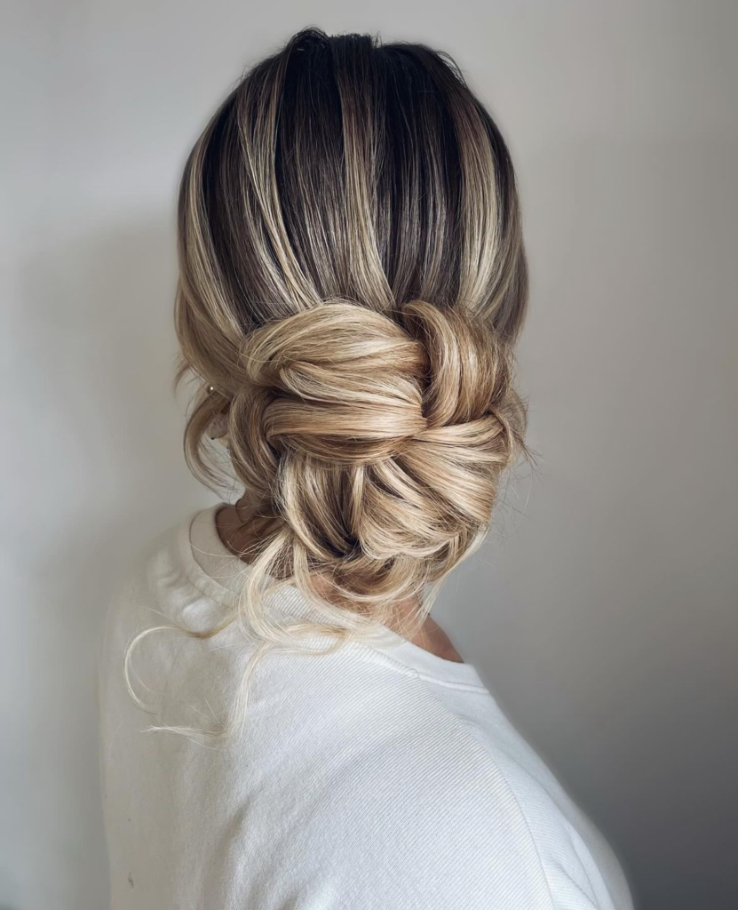 Highlighted blonde woven low knot with interlocking loops and tucked curled ends