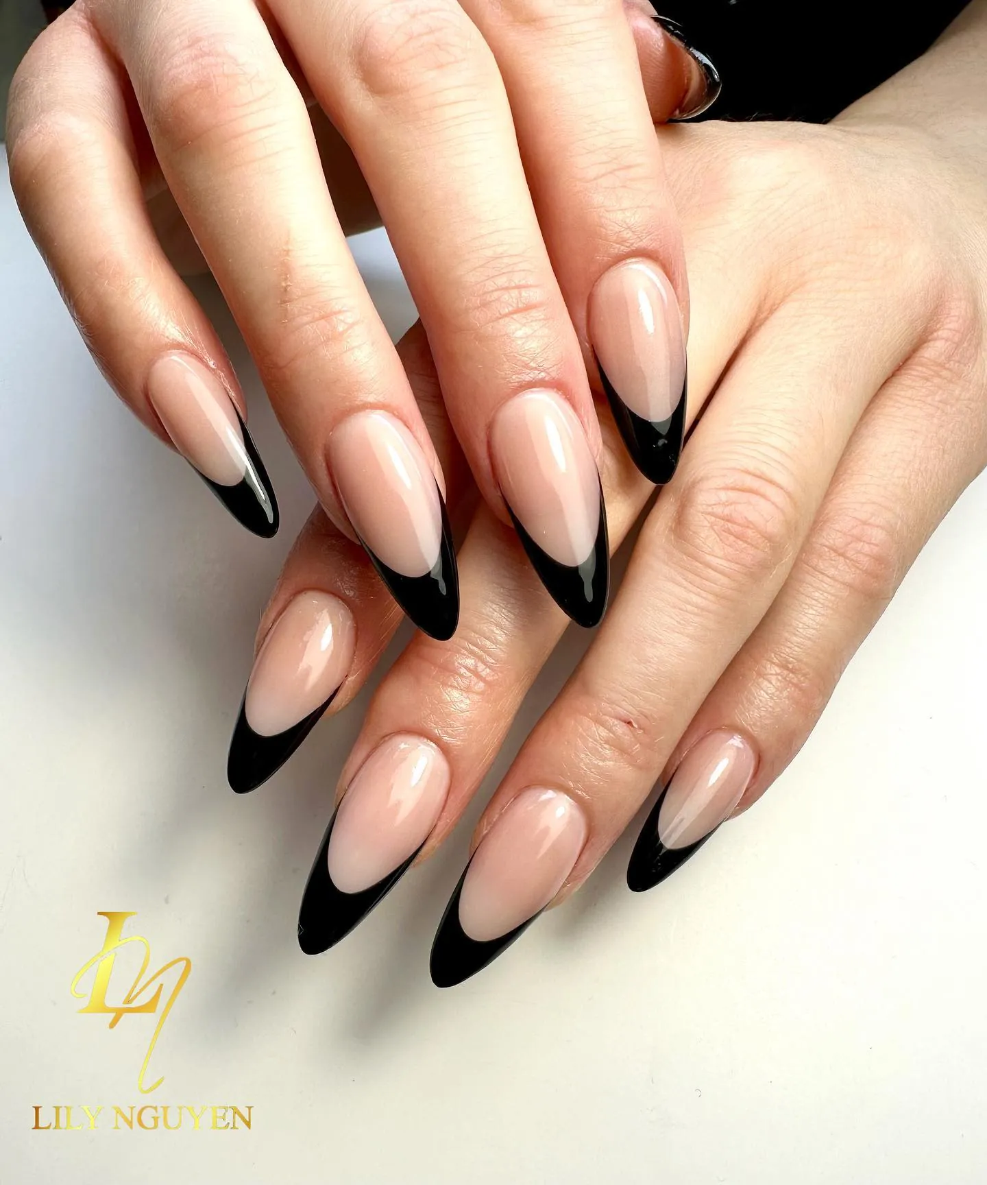Nude almond nails with deep glossy black French tips