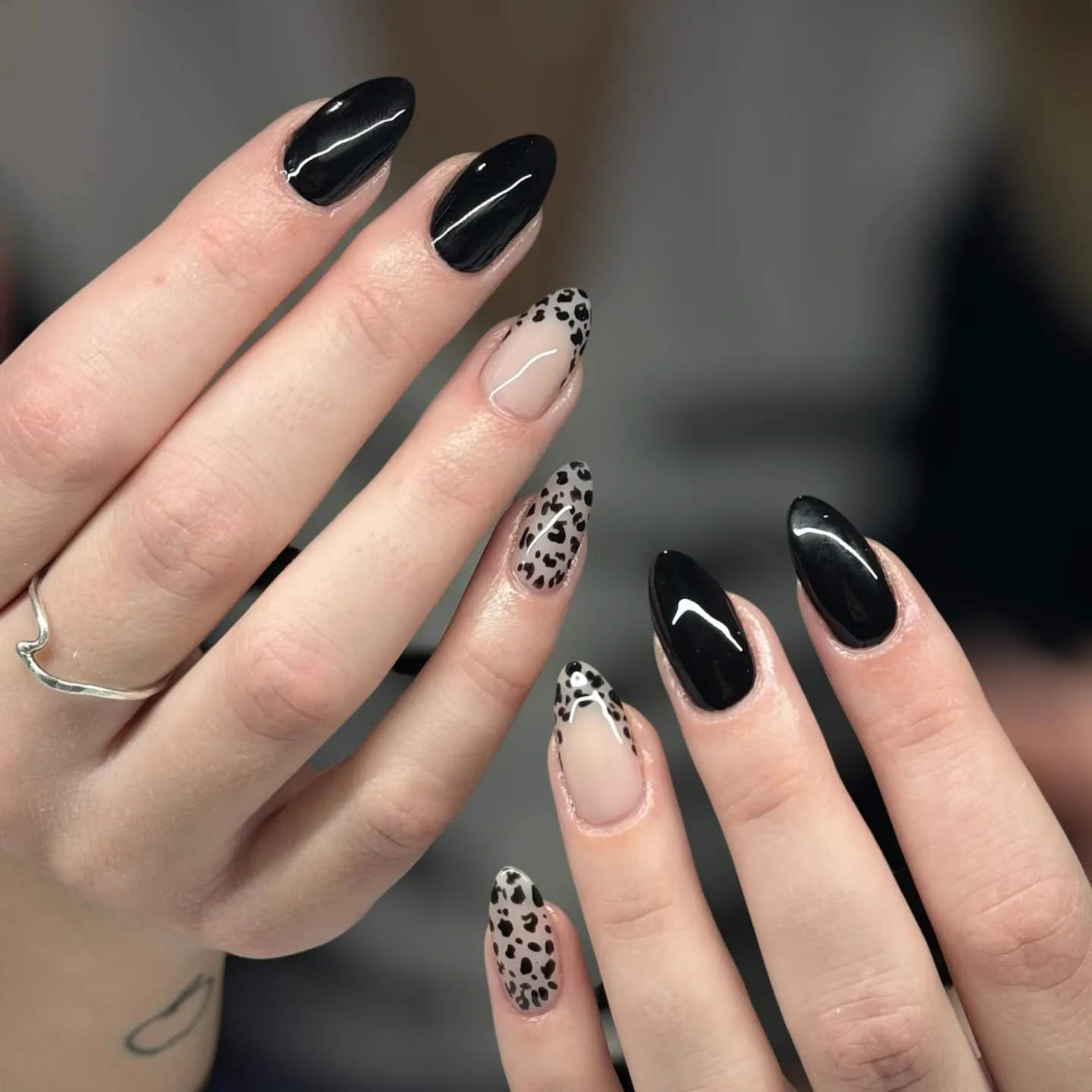Glossy black almond nails with nude leopard patterned accents