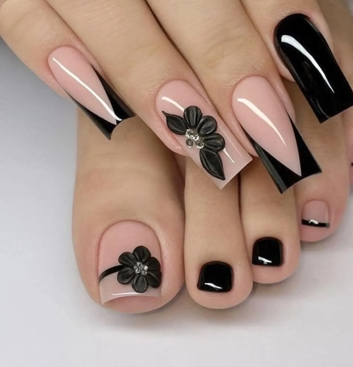 Black and nude manicure with diagonal French tips and matching floral pedicure