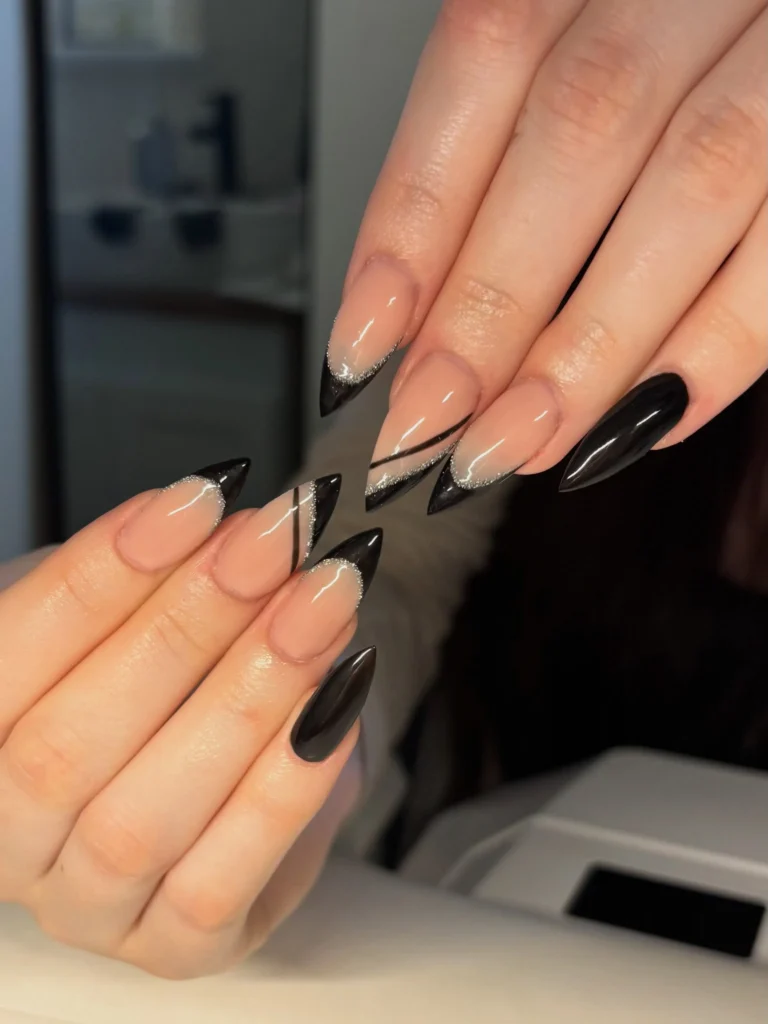 Long almond nails with glossy black polish, nude bases, and angular black French tips