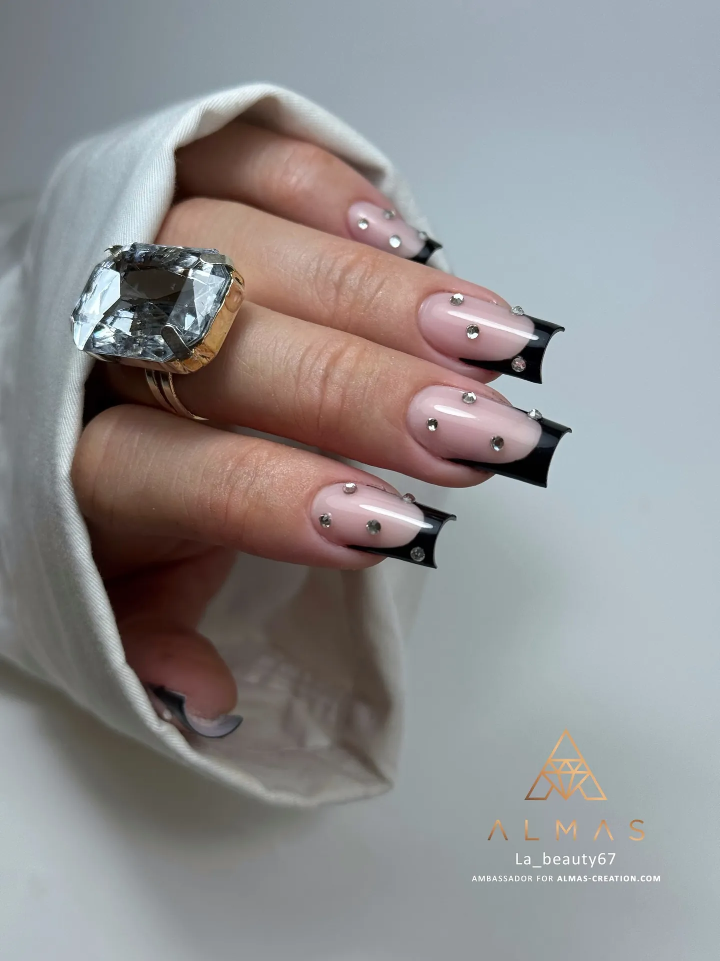 Short nude nails with black French tips and tiny scattered accents