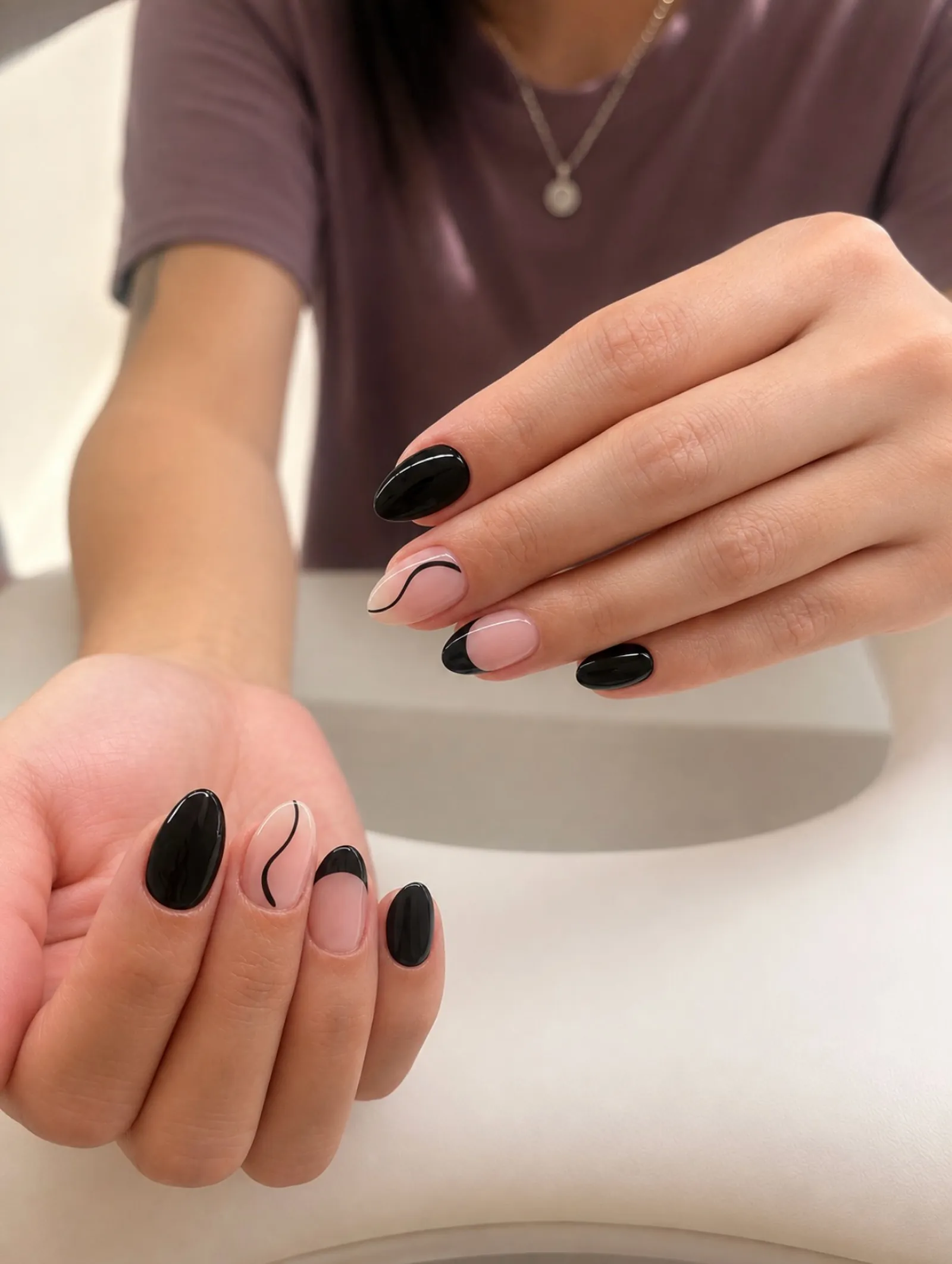 Black oval nails mixed with nude accents and fine black curves