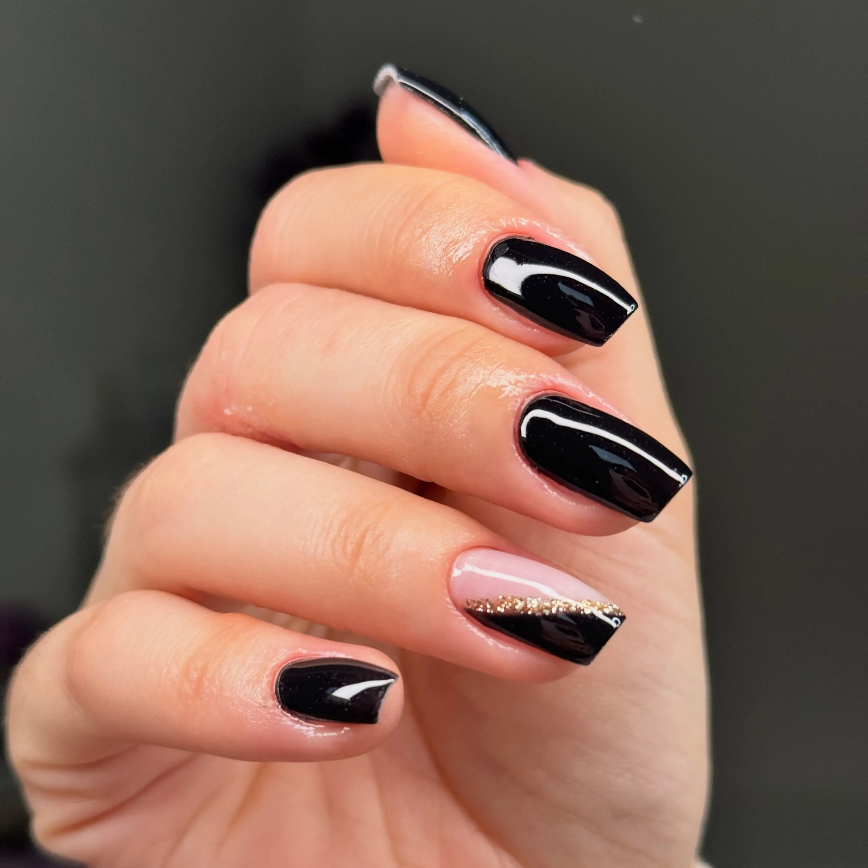Short glossy black nails with a nude diagonal glitter accent