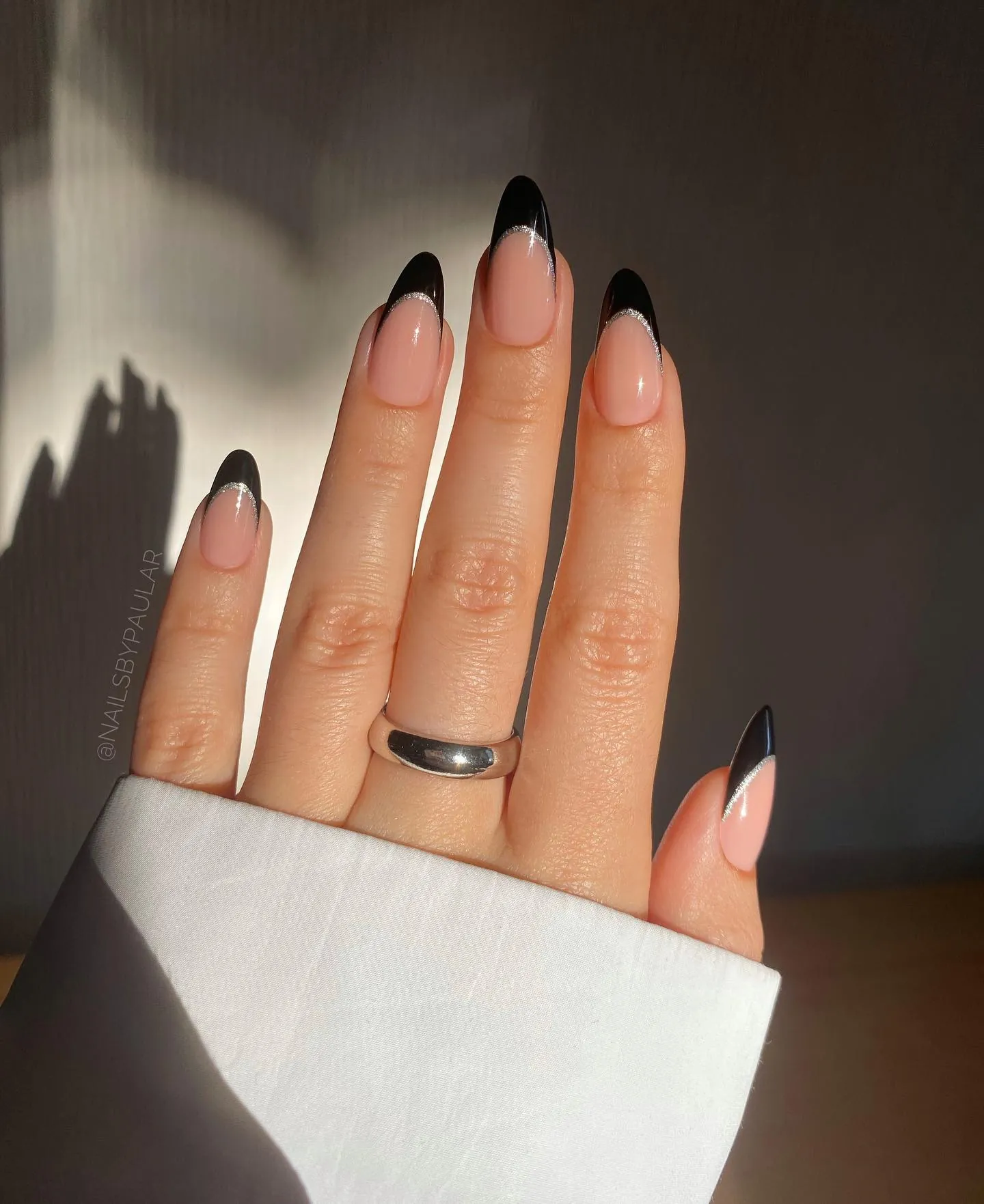 Nude almond nails with pointed black French tips