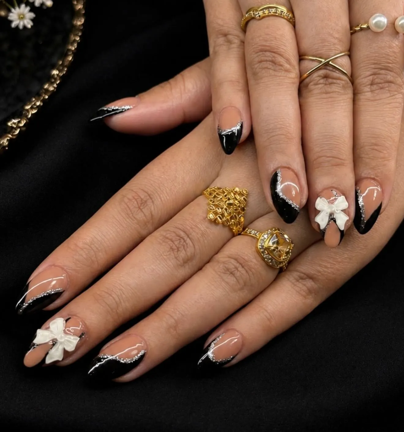 Black French tips with raised white flowers and curved pale accents