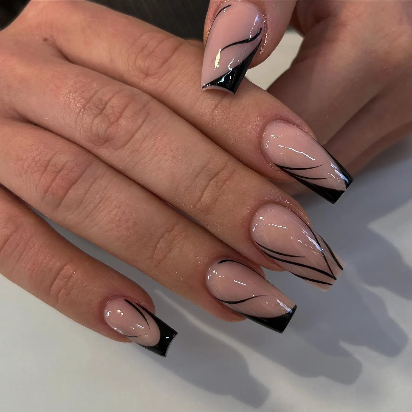 Nude square nails with black French edges and thin curved lines