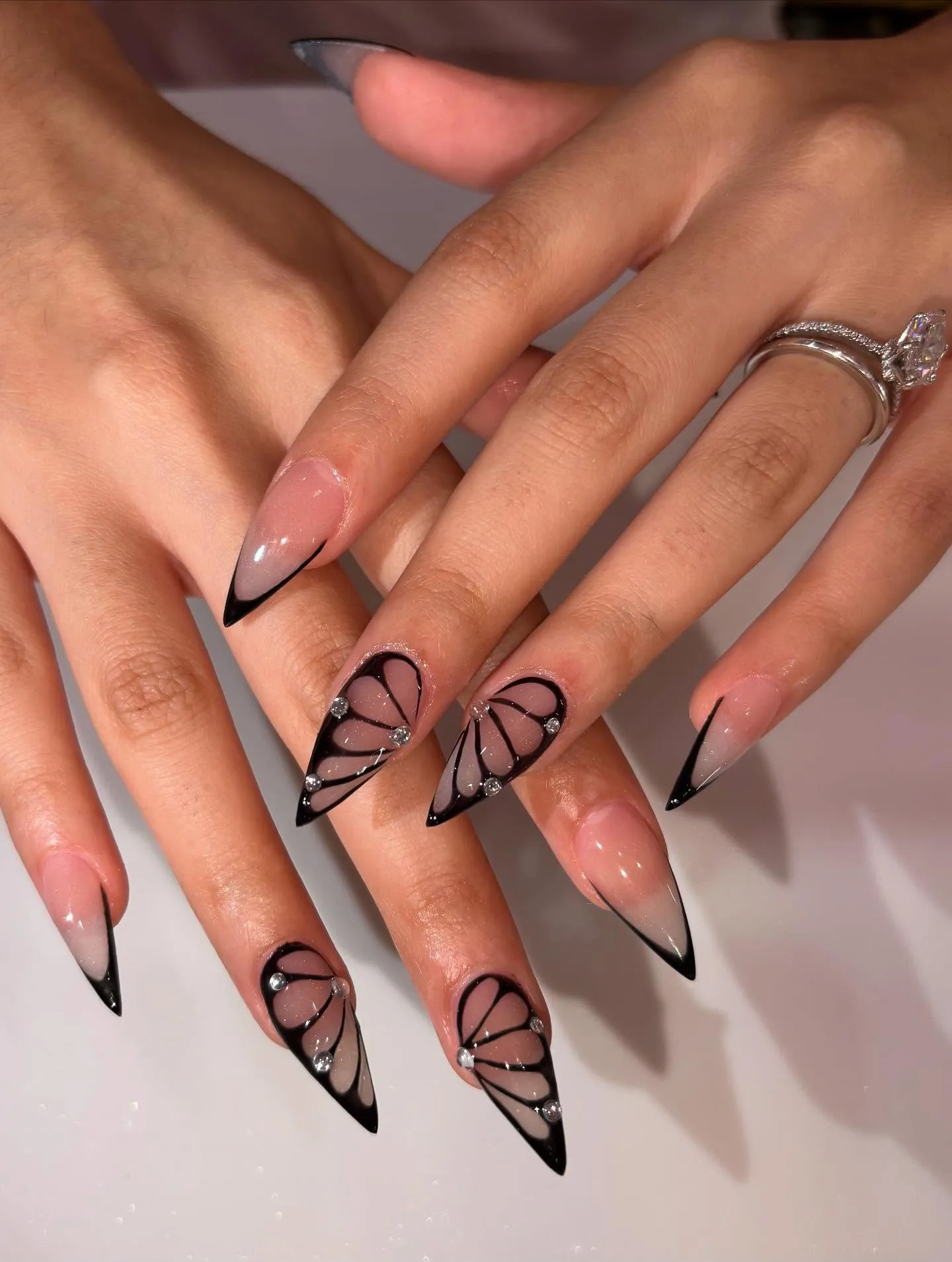 Long nude pointed nails with black tips and looping abstract linework