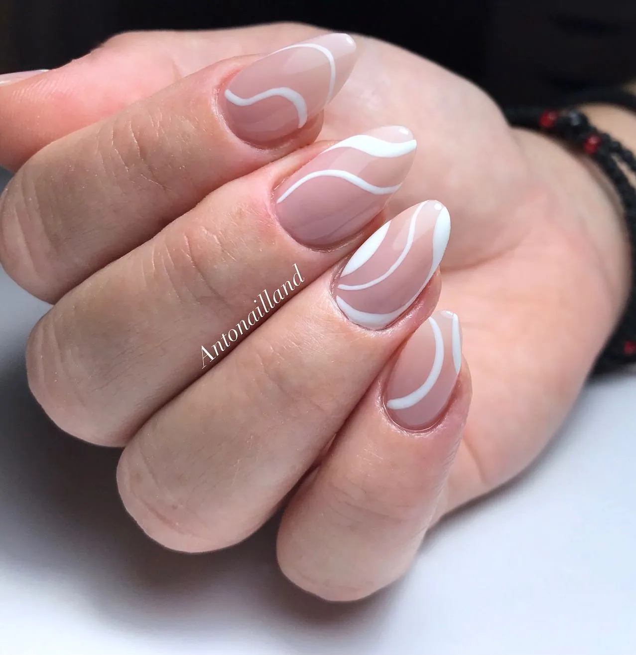 Short nude pink nails with flowing white curved lines