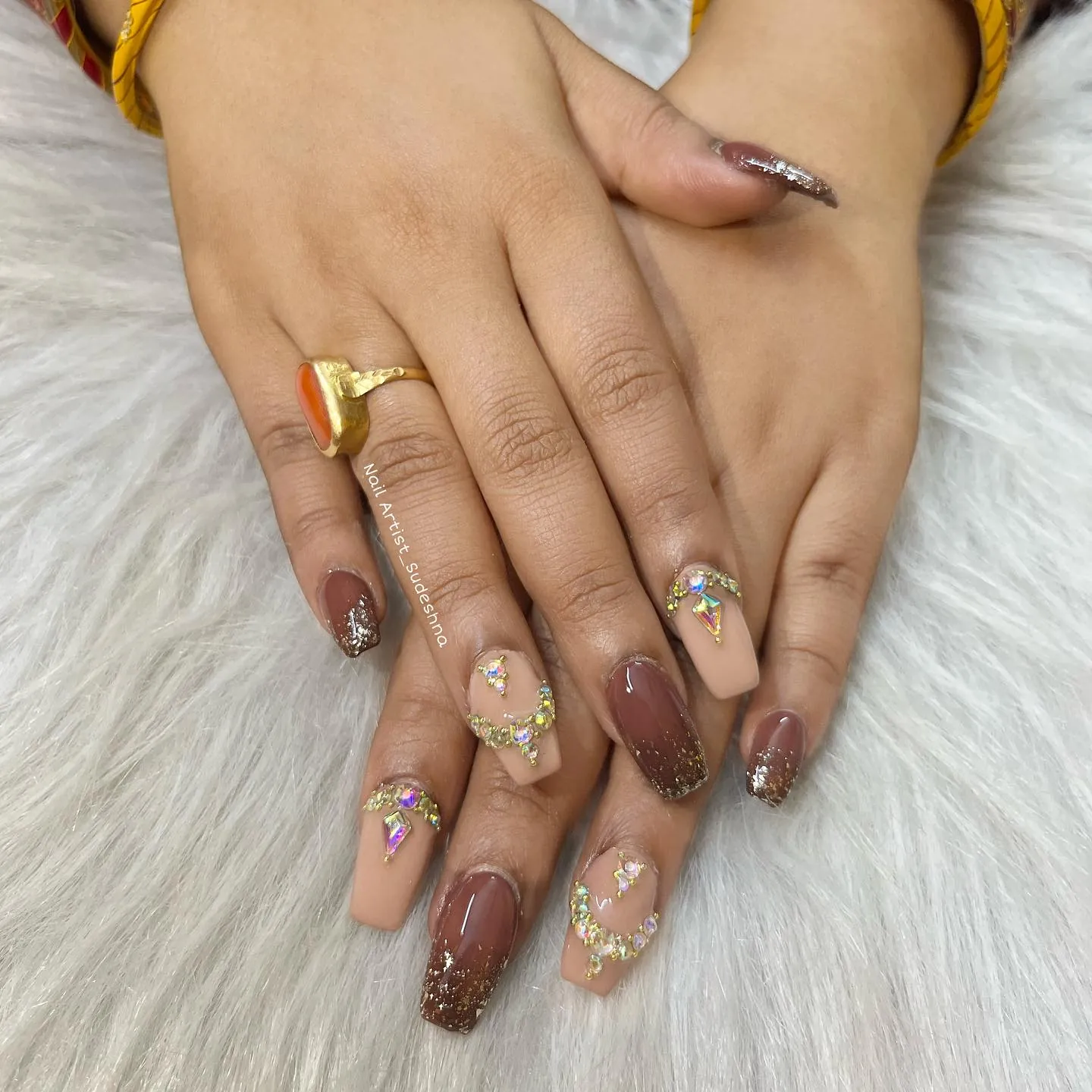 Square brown nails with glitter tips and nude accents decorated with gem clusters