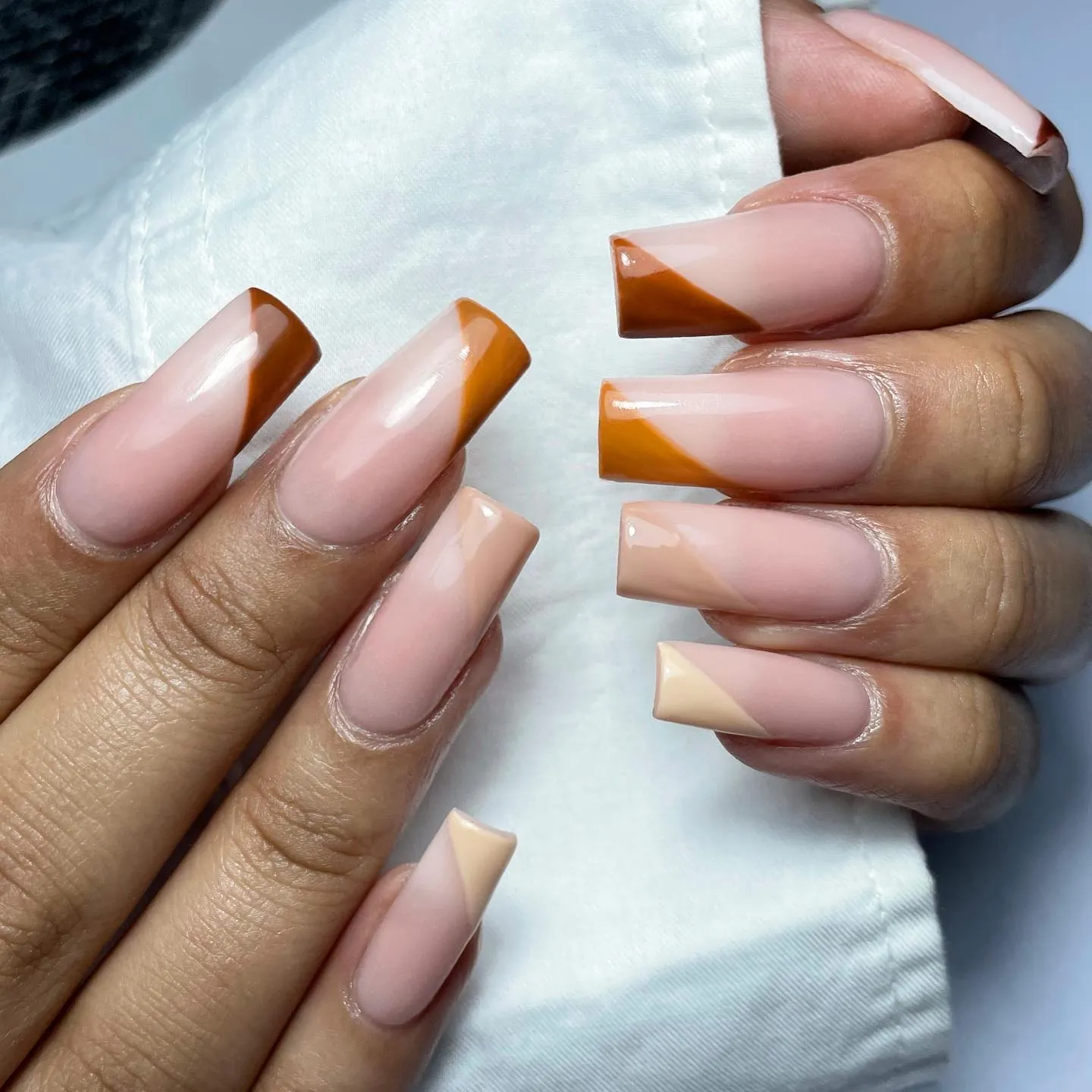 Long square nude nails with French tips in several brown and pale neutral shades