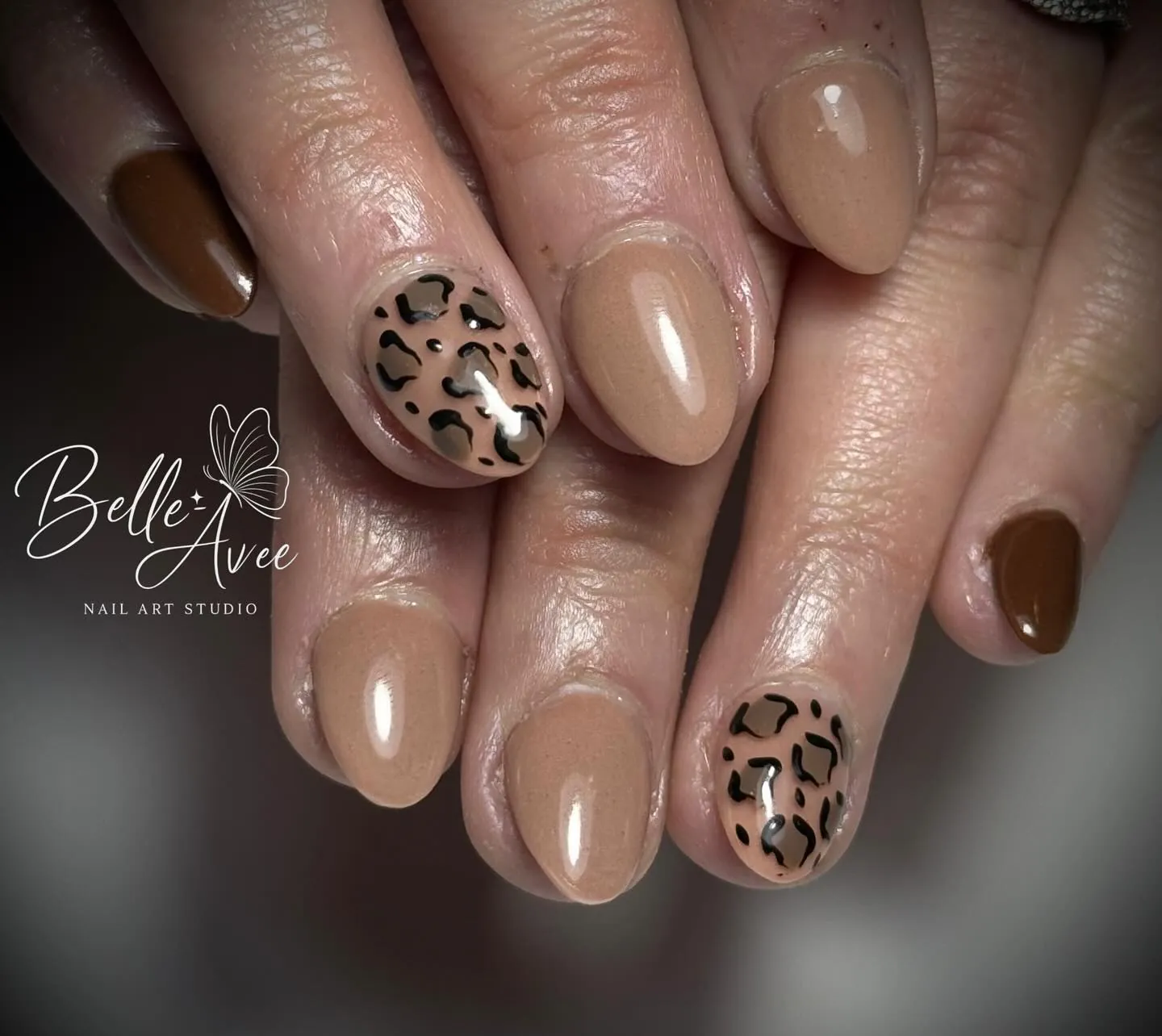 Short rounded nude nails with leopard-print accents and solid brown nails