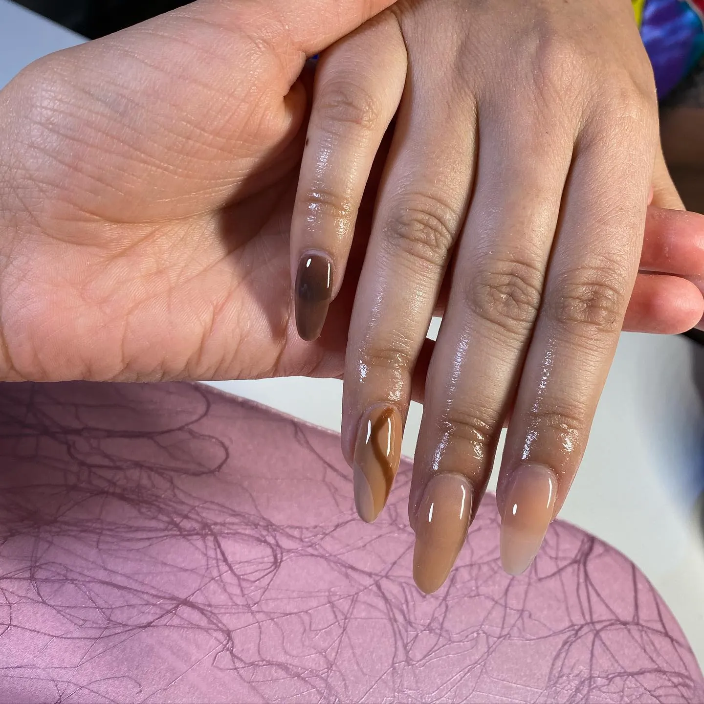 Long almond nails in brown and nude gradients with a curved brown accent