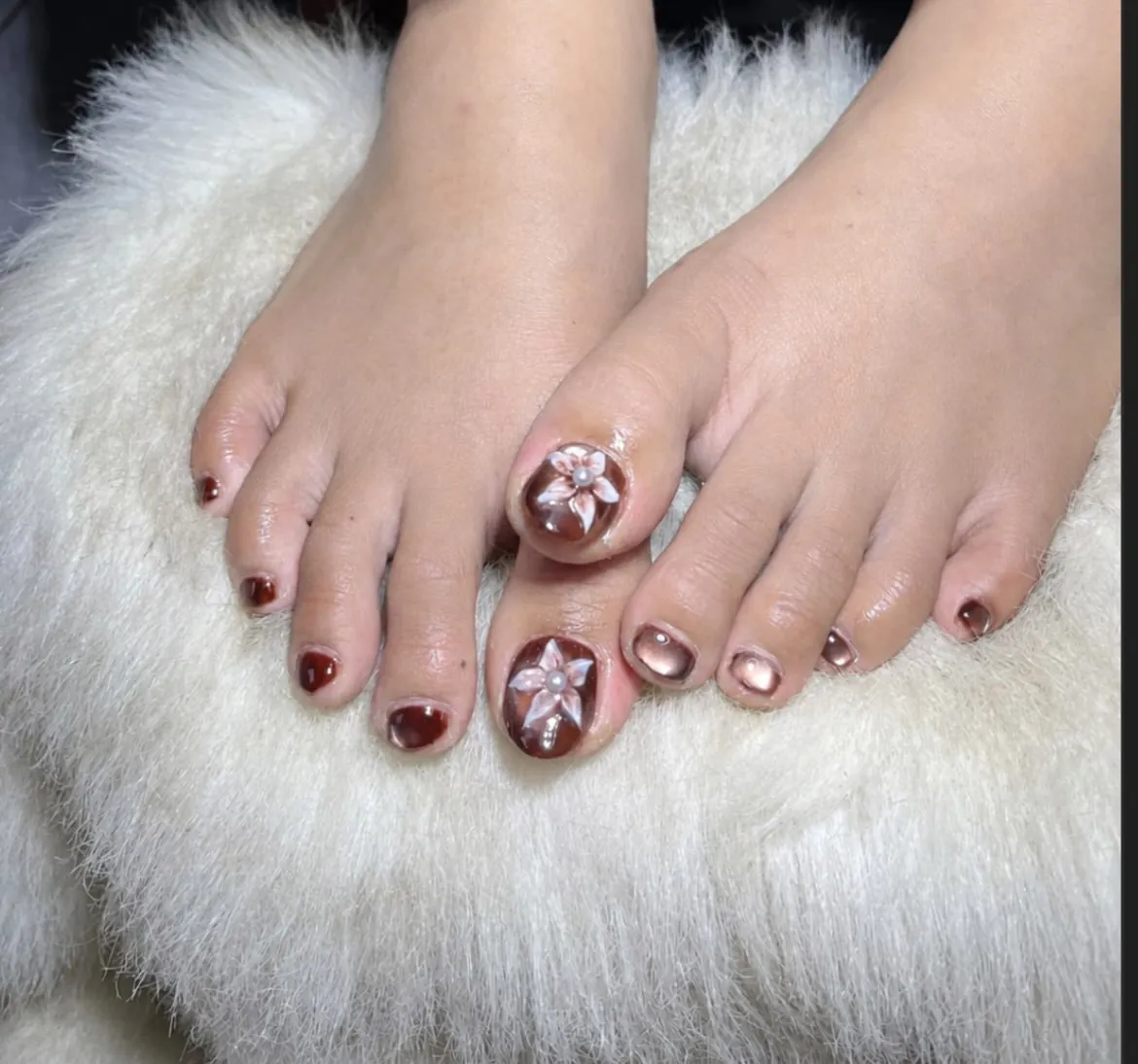 Brown toenails with pale raised flowers and reflective pink-brown accents