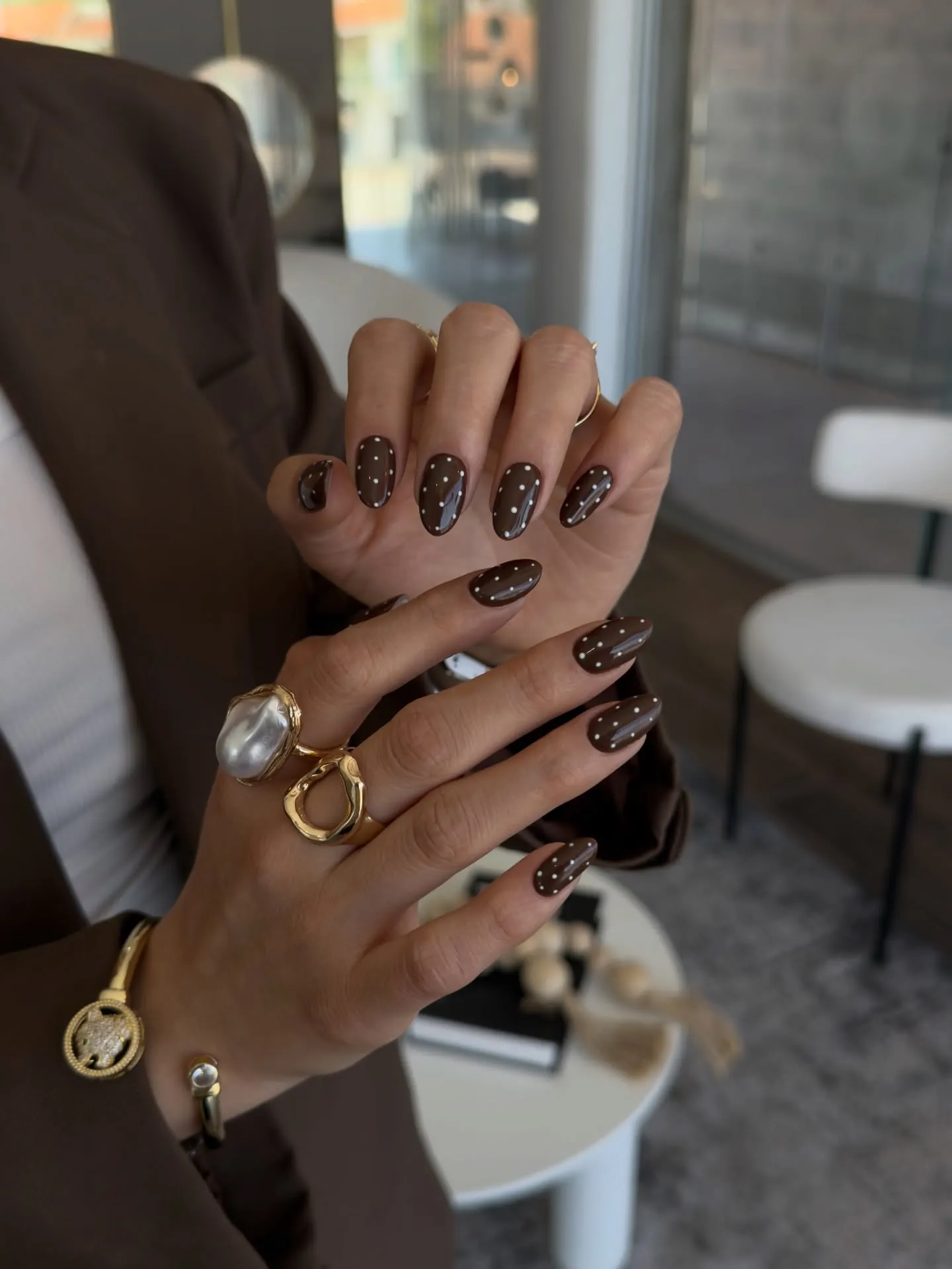 Glossy dark brown oval nails with small evenly spaced pale dots
