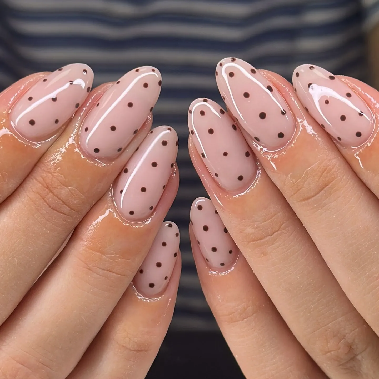 Pale pink almond nails with small scattered brown polka dots