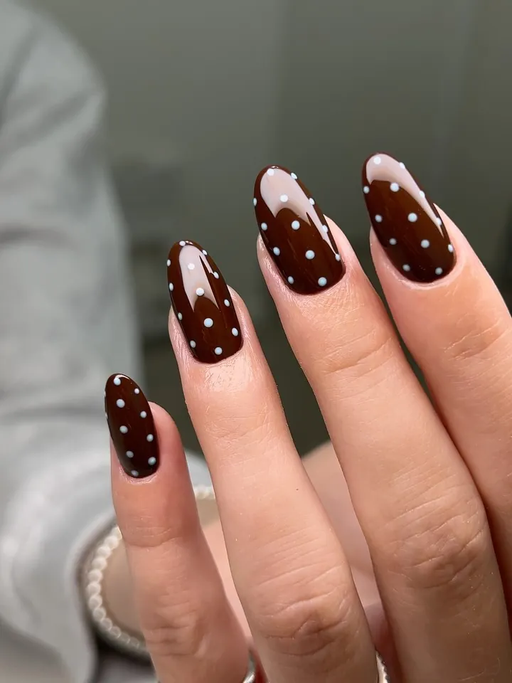 Long dark brown almond nails with evenly spaced white polka dots