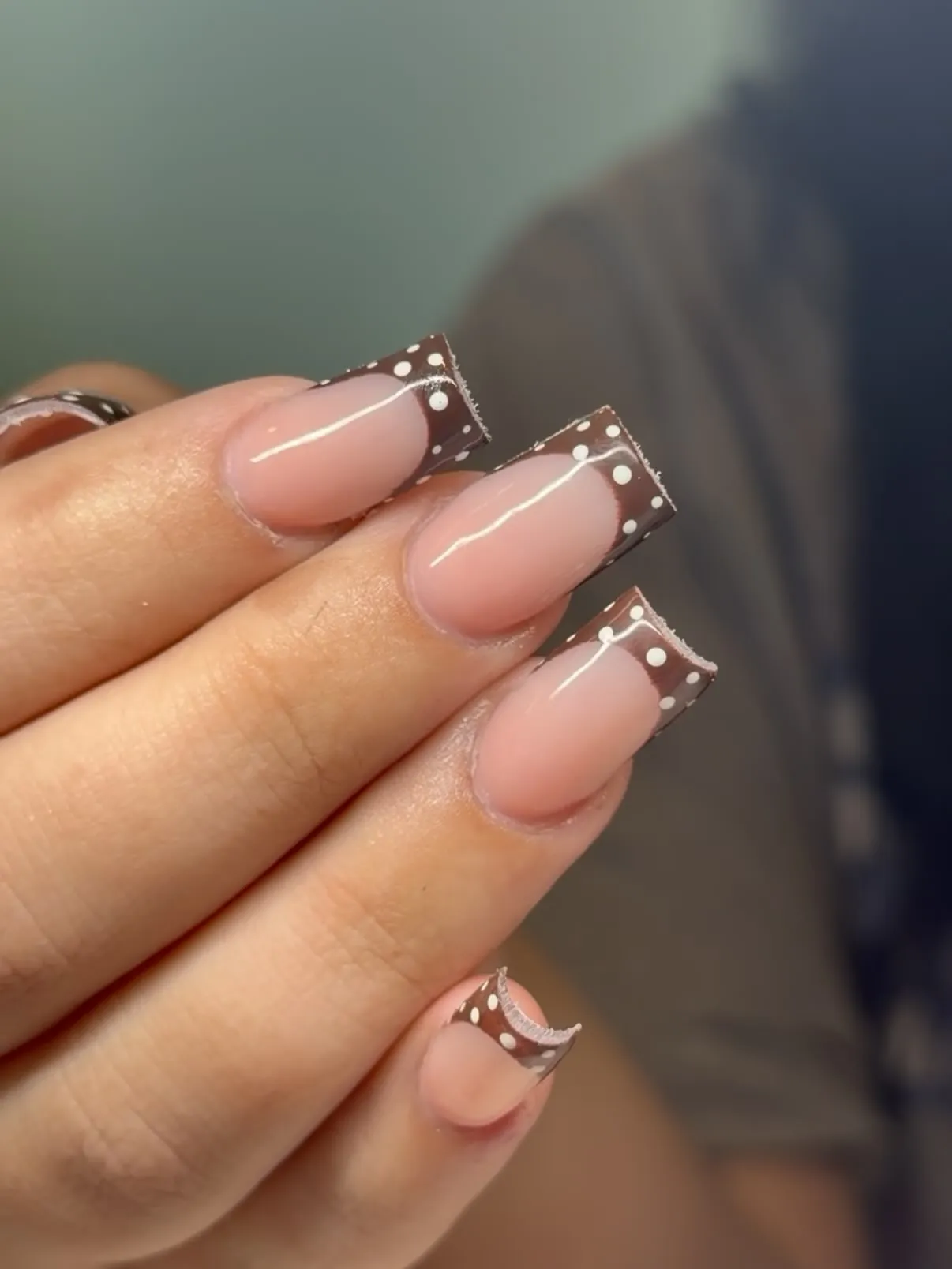 Long square pink nails with brown French tips and small white dots