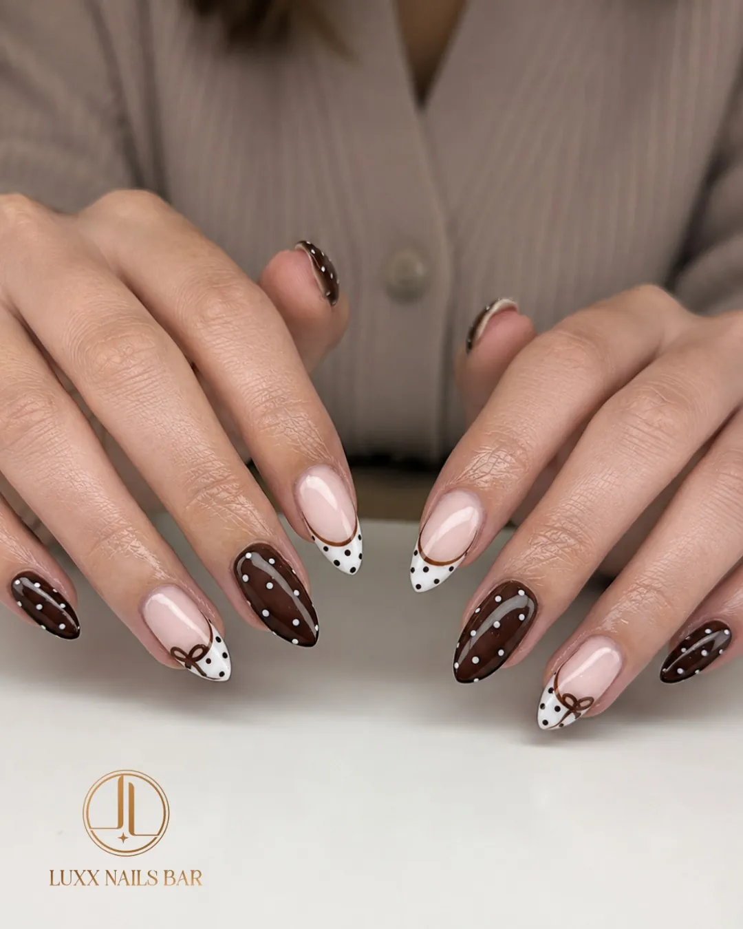 Brown dotted almond nails with dotted white French tips and fine brown bows
