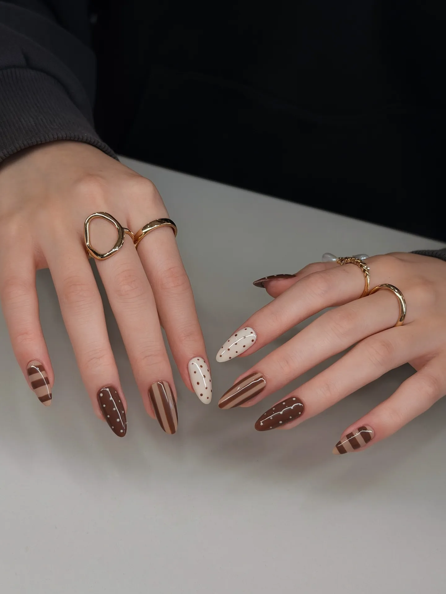 Almond nails with brown stripes, pale dotted accents and brown nails with white dots