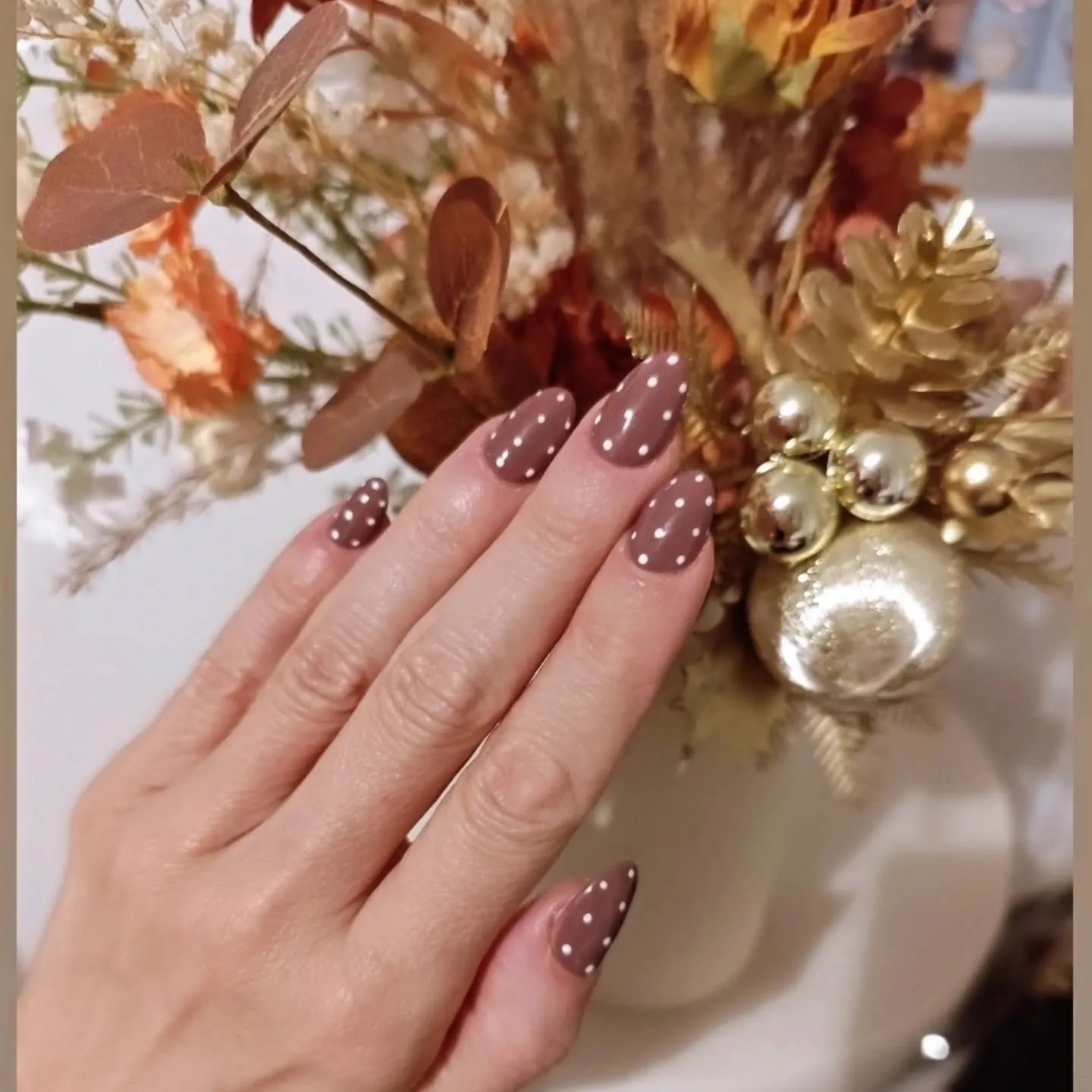 Muted reddish brown almond nails with pale polka dots