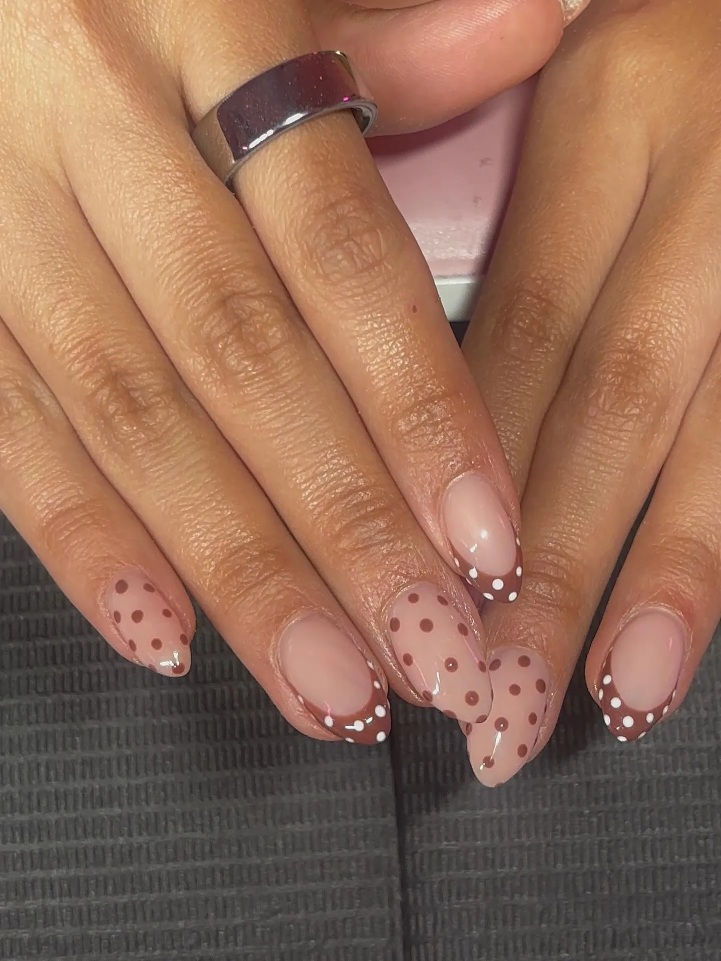 Pink almond nails with brown dotted accents and brown French tips with white dots