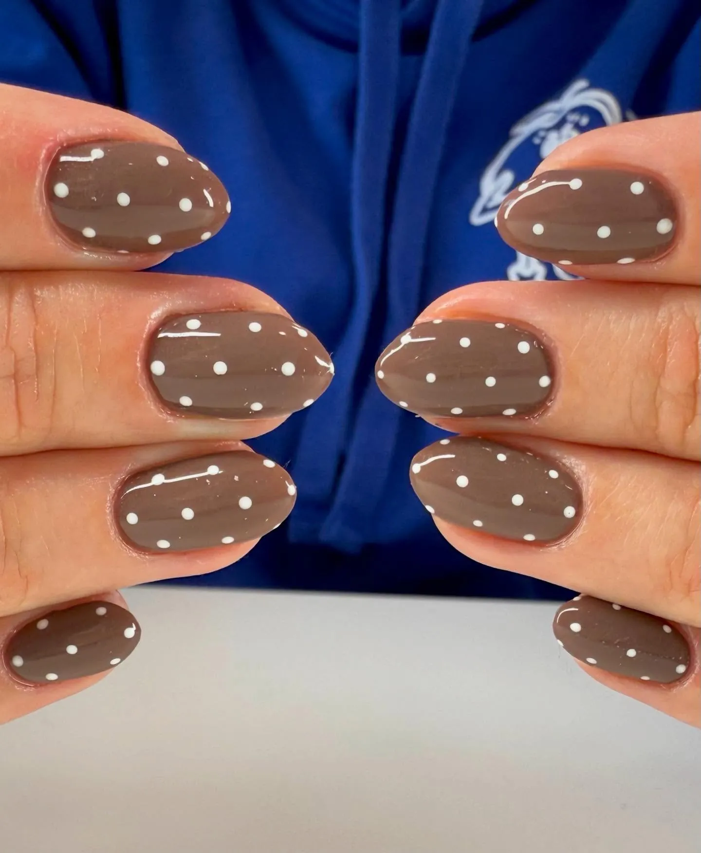 Glossy brown oval nails with widely spaced white polka dots