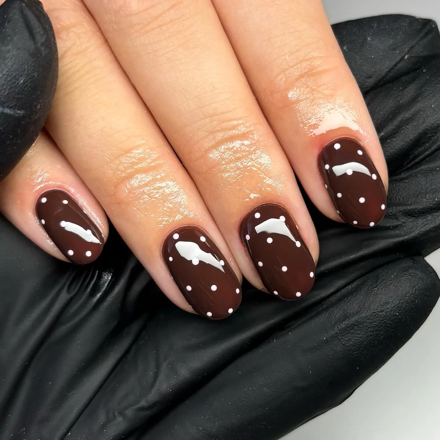 Short rounded square brown nails with scattered small white dots