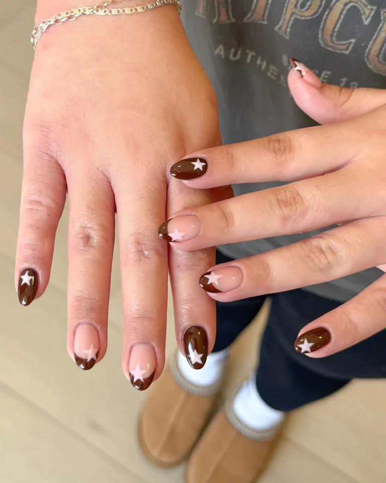 Glossy chocolate brown almond nails with white star accents and nude nail art designs.