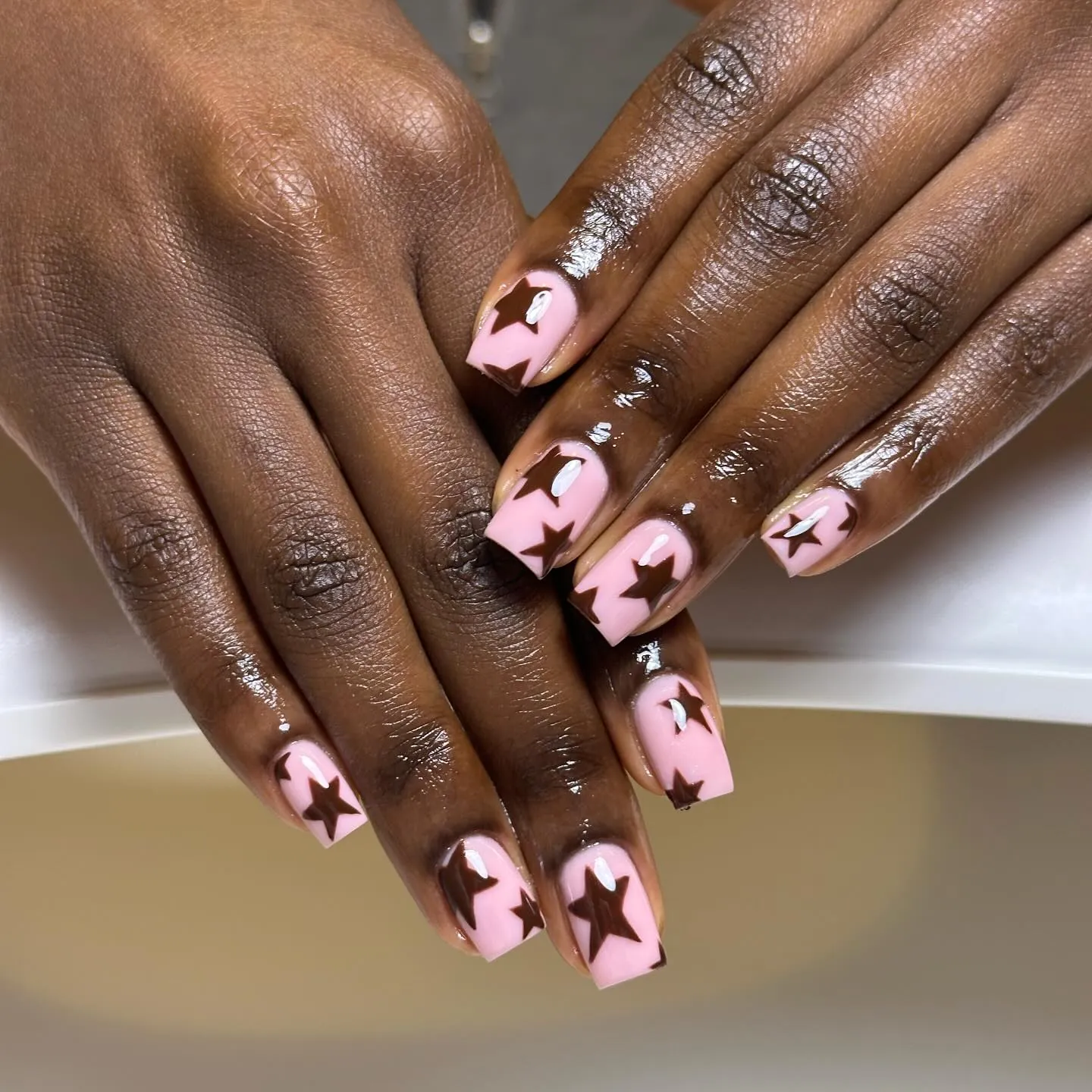 Long square light pink nails decorated with oversized chocolate brown stars