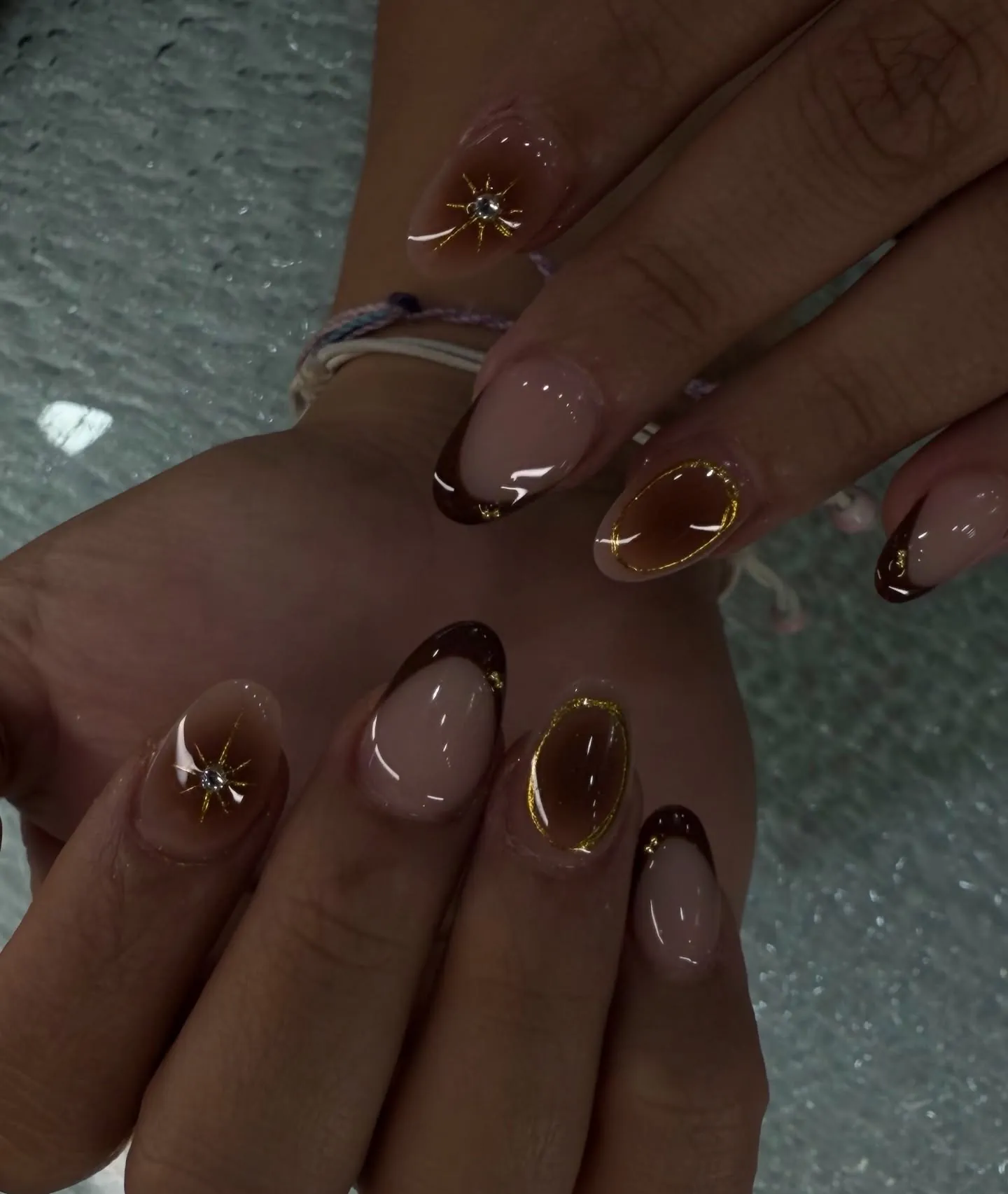 Mocha brown French nails with gold starburst details and translucent nude bases