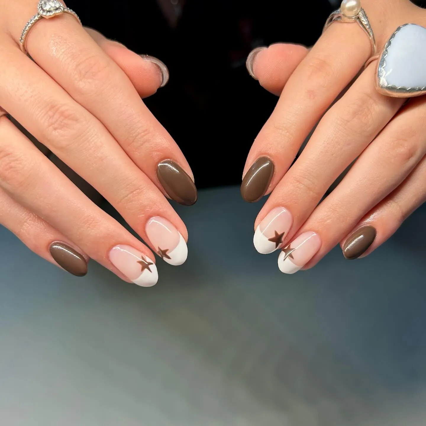 Short oval taupe nails with pale French tips and small brown stars