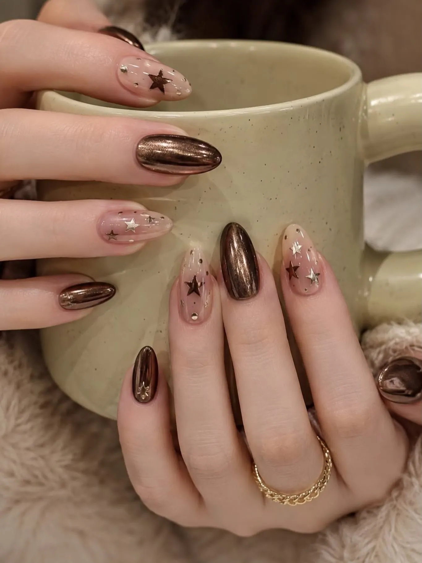 Bronze chrome nails paired with sheer pink nails and tiny brown stars