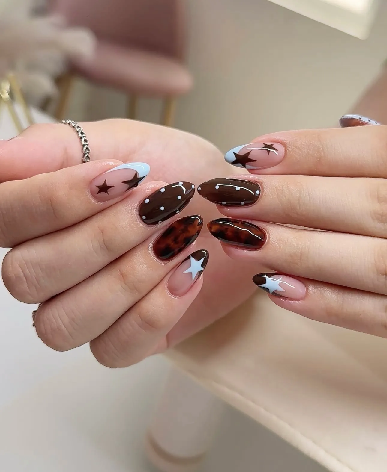 Almond nails with espresso accents, white tips and brown stars