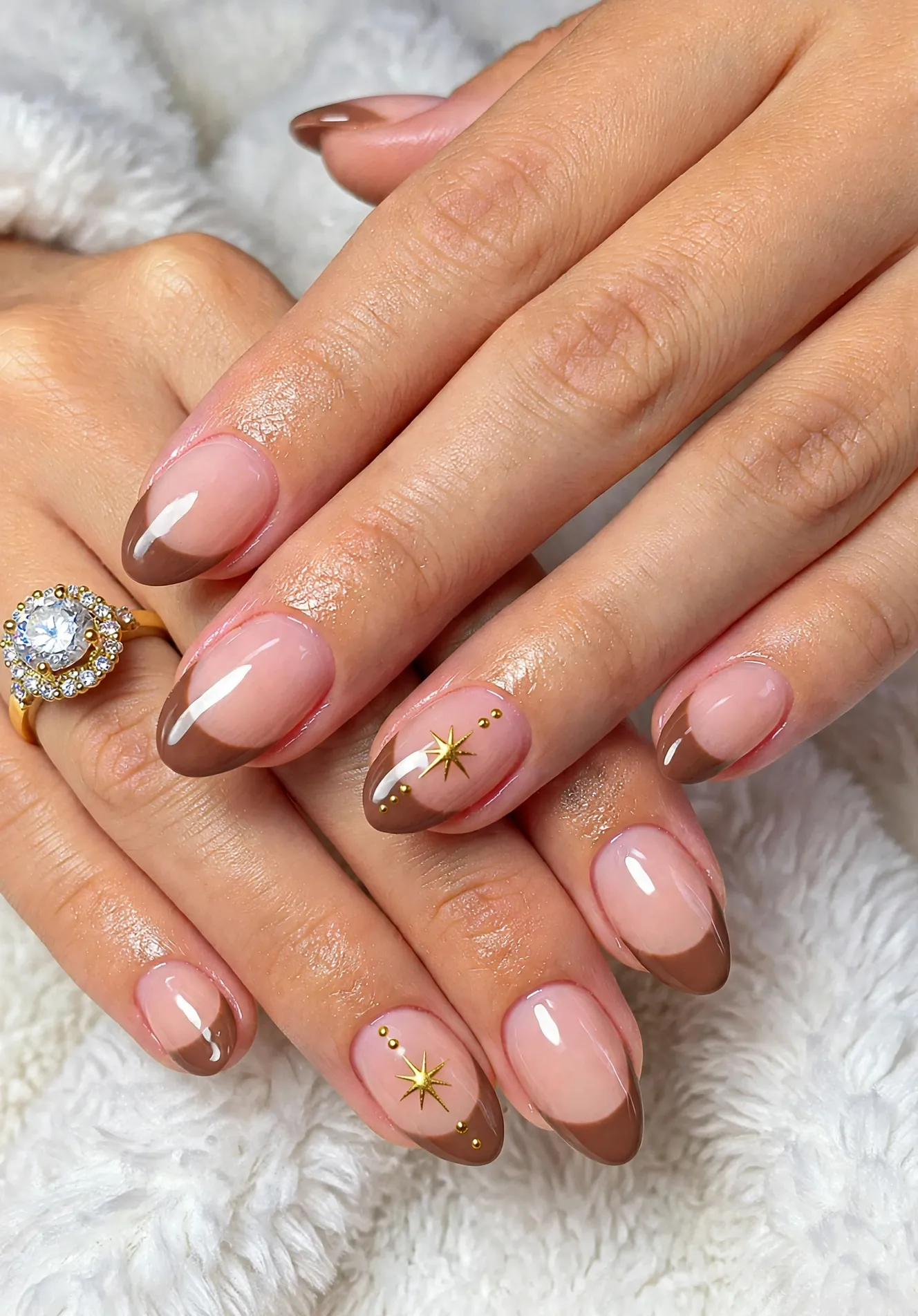 Short nude oval nails with fine brown French tips and small gold stars