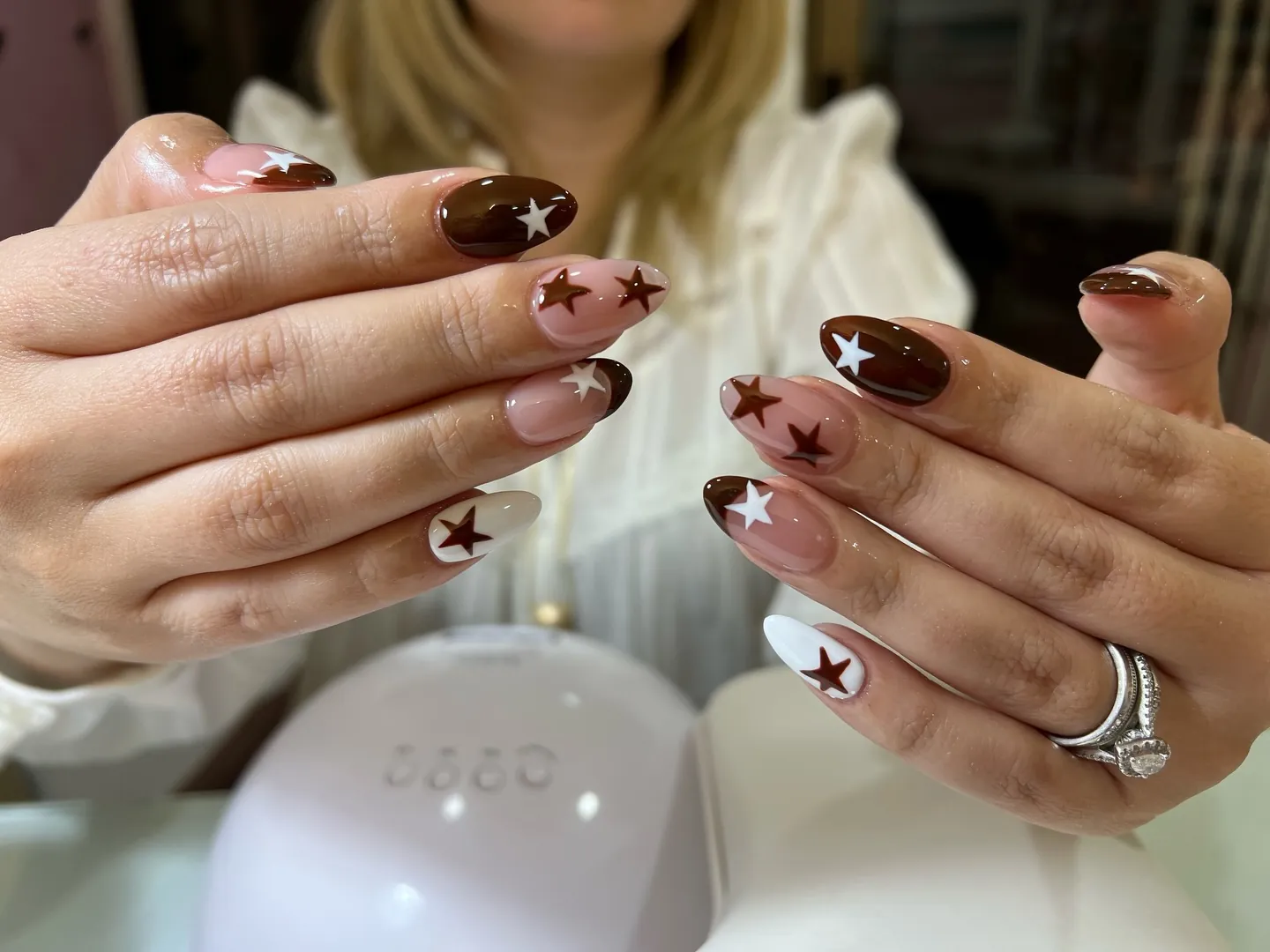 Long nails with chocolate brown stars on nude and white backgrounds