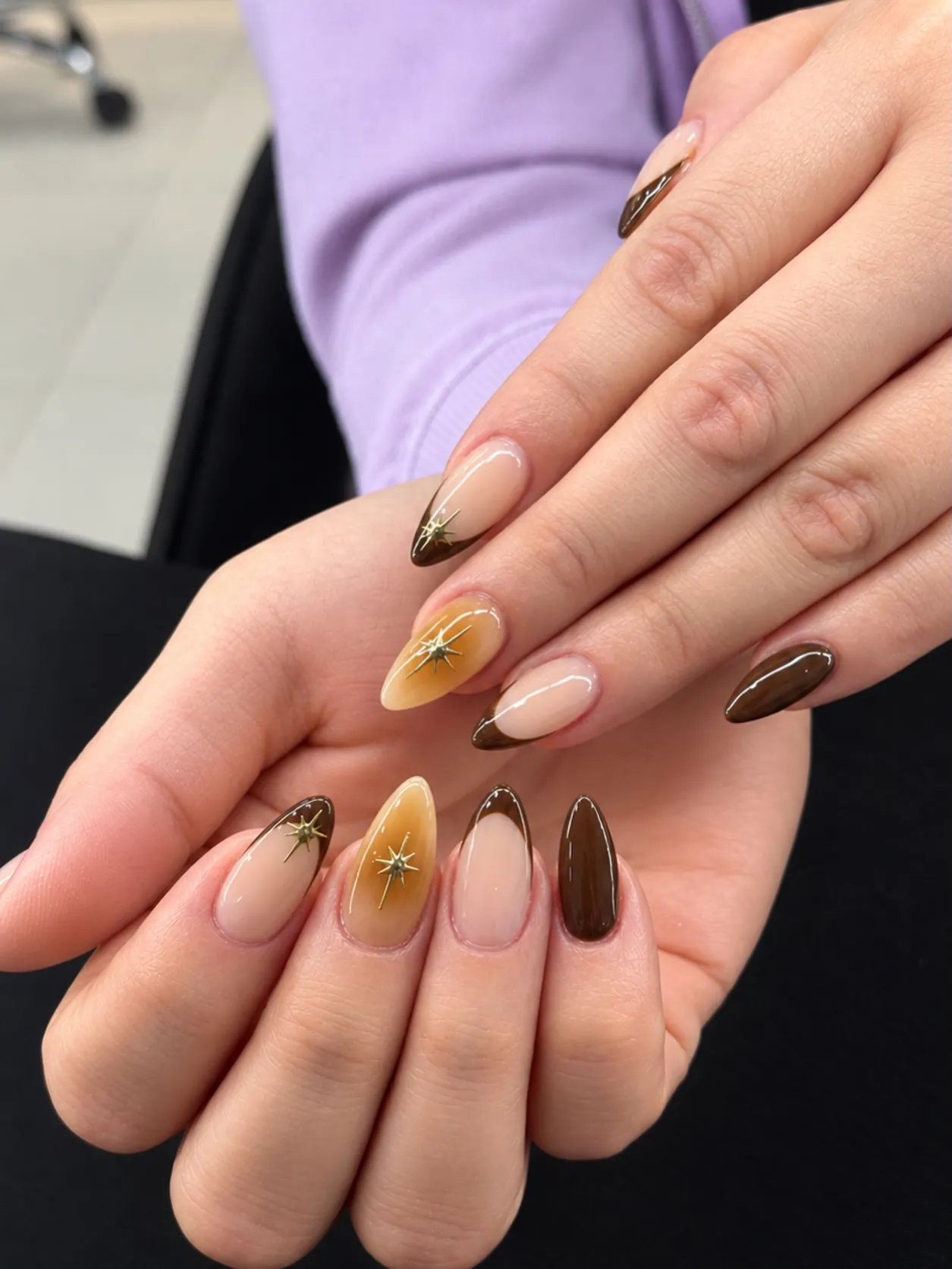 Long almond nails in caramel, deep brown and nude with gold starbursts