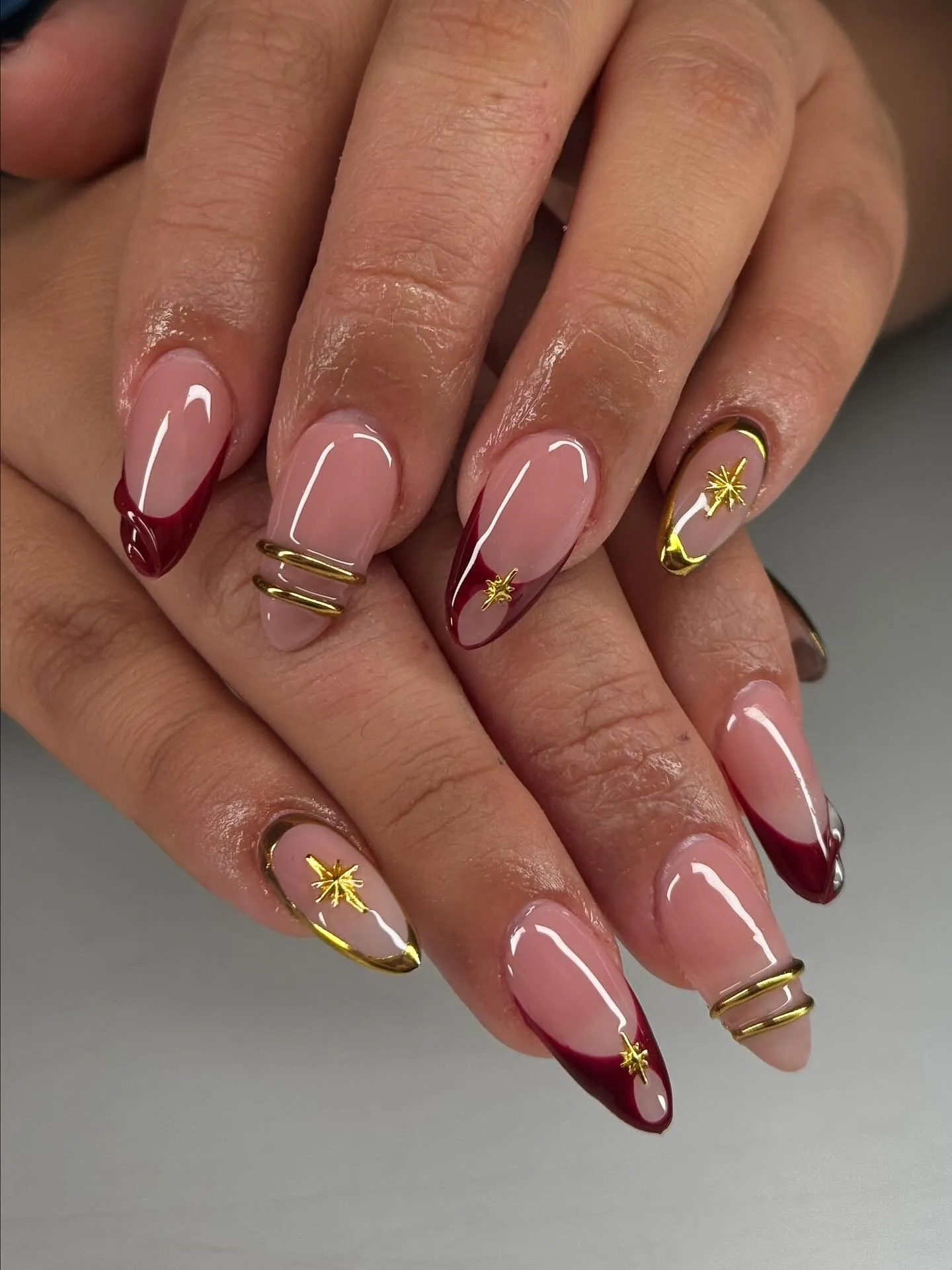 Burgundy French tips with gold star accents frames and raised bands
