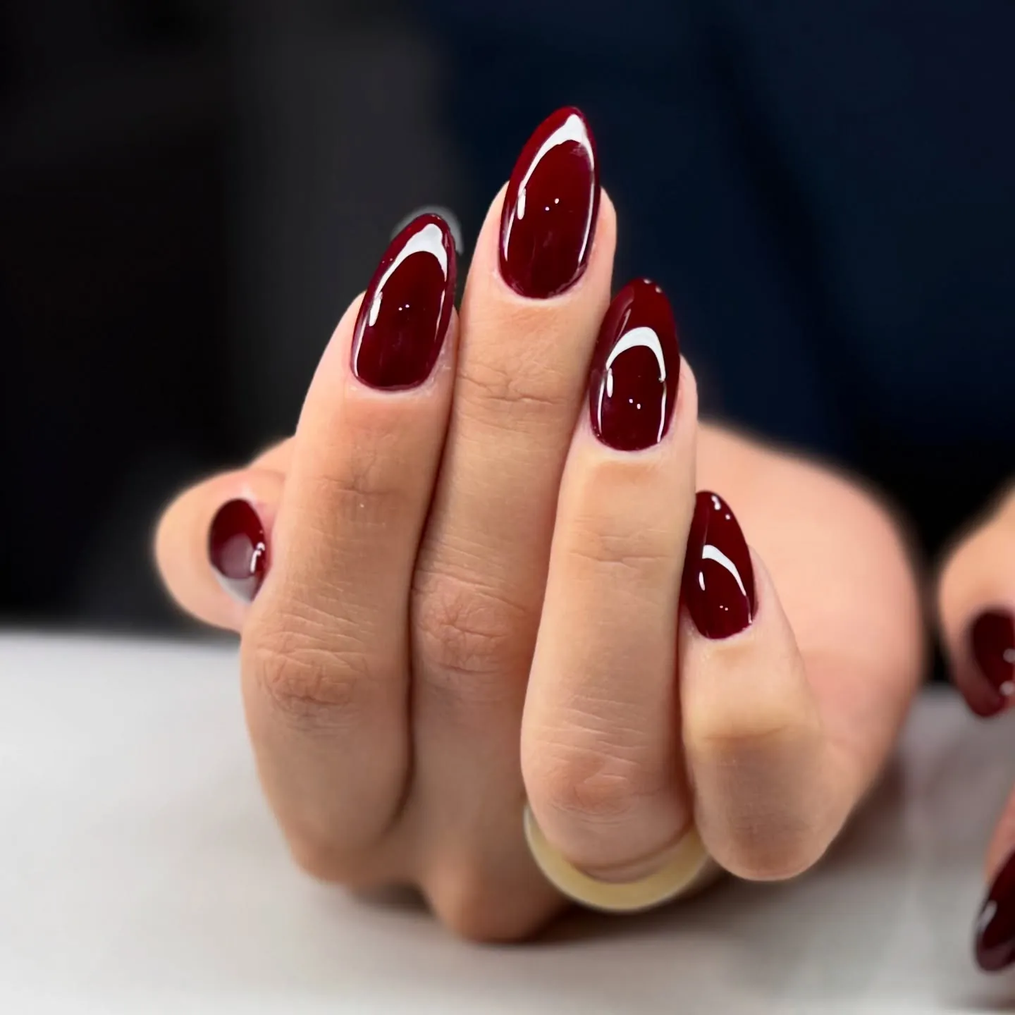 Rounded almond nails with glossy red burgundy polish