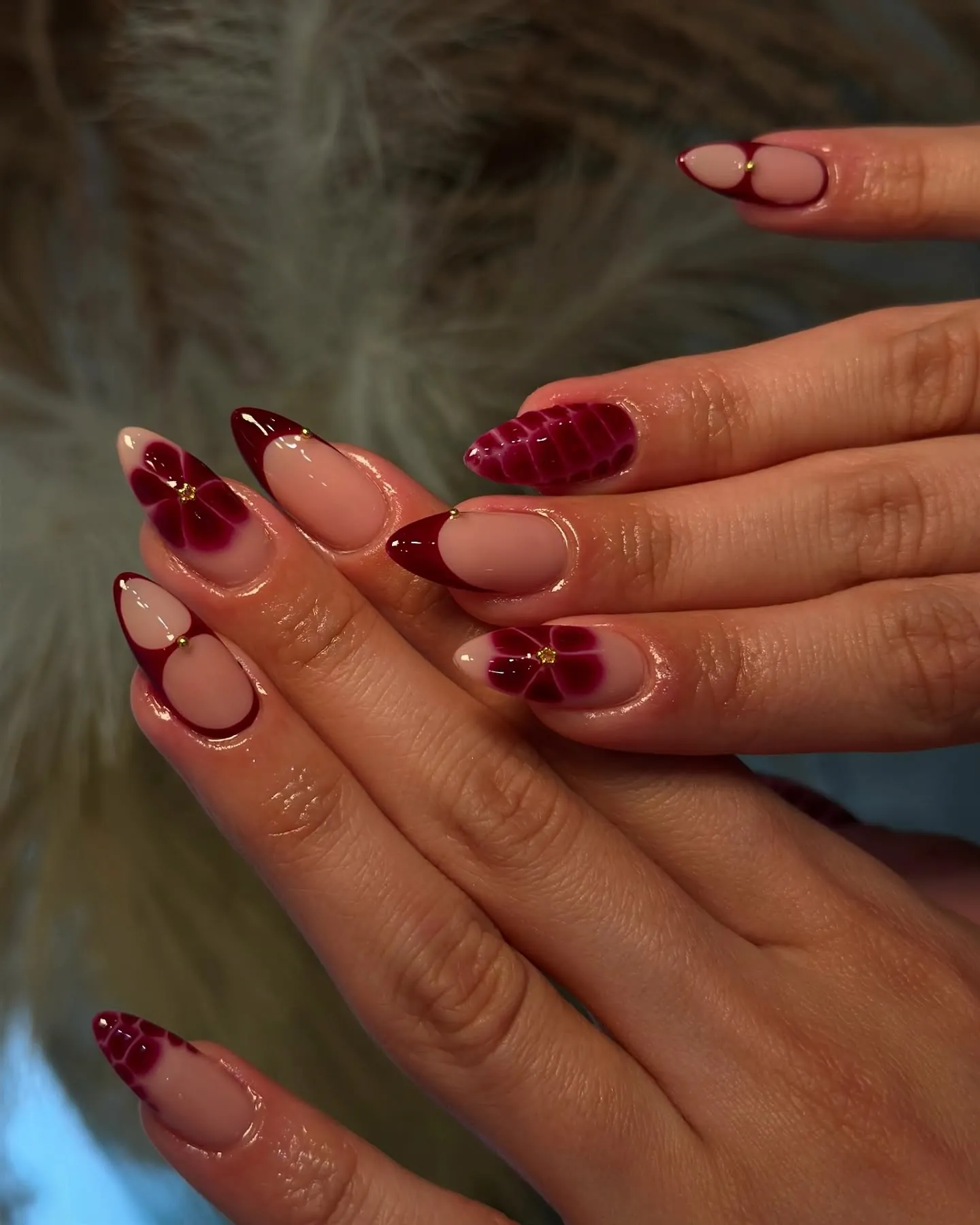Burgundy almond nails with nude outlines flowers and reptile patterned accents
